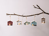 Beautiful festive new year and Christmas decorative little wooden houses hanging on a stick on the grey wall background, with fireflies glowing on the foreground