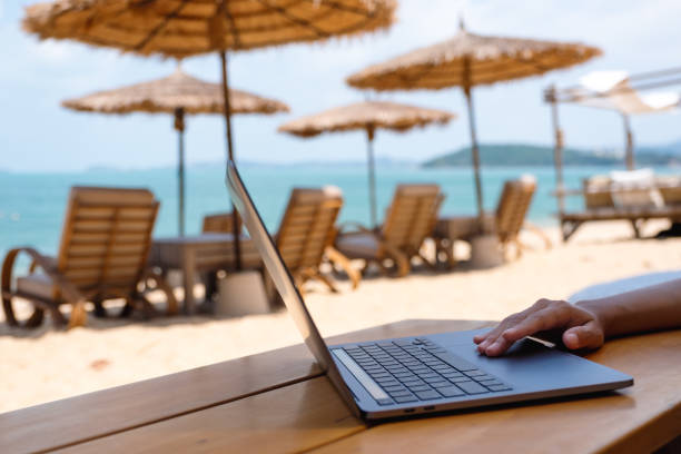 a woman working and touching on laptop touchpad on the beach Closeup of a woman working and touching on laptop touchpad on the beach digital nomad stock pictures, royalty-free photos & images