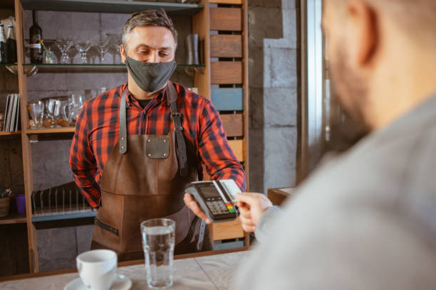 istock Waiter wearing a facemask while getting a contactless payment at a restaurant 1306313320