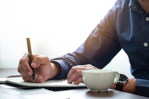 istock Businessman hand holding writing pen memo into notebook paper on table desk office. Workplace for business and student, writer with copy space. business working and learning education concept. 1306314798