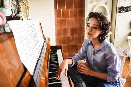 Young beautiful woman playing piano at home