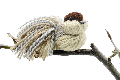 Yarn birds made of wool sit on a twig