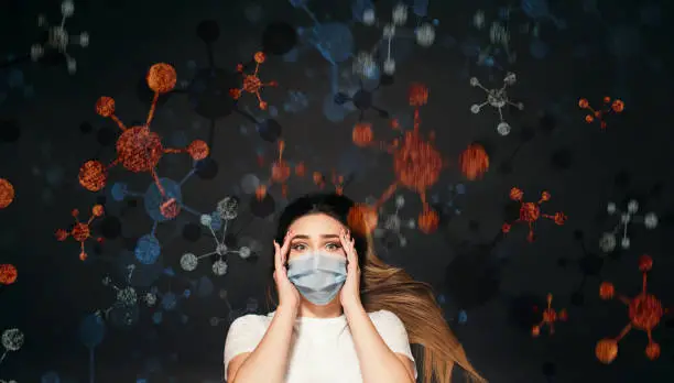 Photo of young woman on black studio background in protective medical mask surrounded by disease virus, frightened girl, concept health