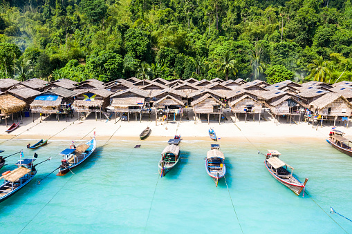 Aerial view of Ko Surin Marine National Park. Traditional long-tail boats and houses of Moken tribe Village or Sea Gypsies and tropical waters of Surin Islands in Thailand, Phang Nga.