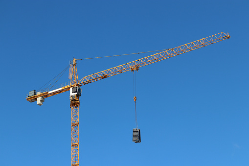 Construction crane lifting the cargo on blue sky background