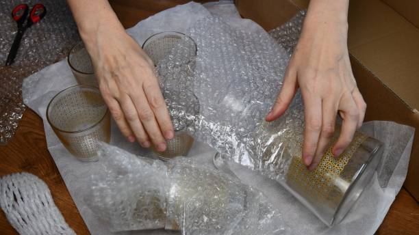 istock Female hands packing up glassware into plastic bubble wrapping 1306319892