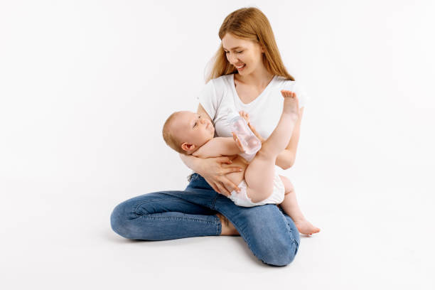 istock Happy smiling mother feeding her baby from a bottle, on white background 1306321673
