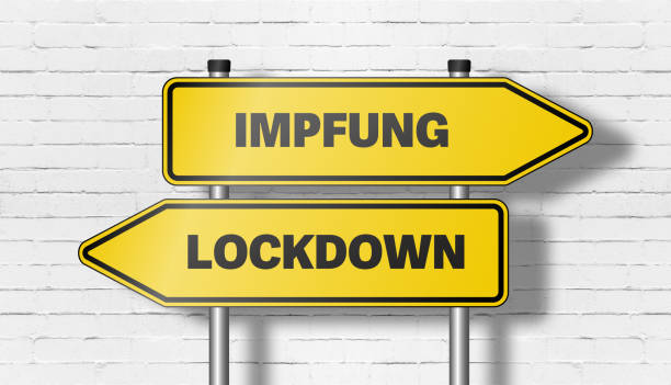 istock signpost with directional road signs pointing in both directions with words IMPFUNG, German for vaccination, and LOCKDOWN 1306324069