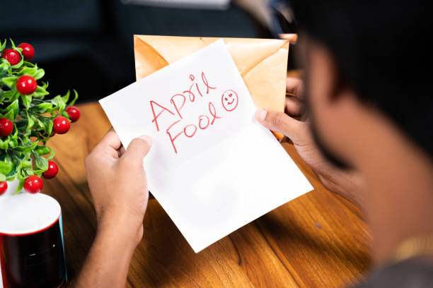 Shoulder shot of young man receiving prank latter - Concept of April fools day prank showing by sending surprise letter, after opening mentioned april fool in the latter. Shoulder shot of young man receiving prank latter - Concept of April fools day prank showing by sending surprise letter, after opening mentioned april fool in the latter April Fools Pranks stock pictures, royalty-free photos & images