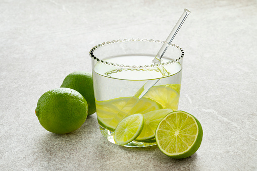 Fresh green limes and glass of water with lime slices as a healthy drink