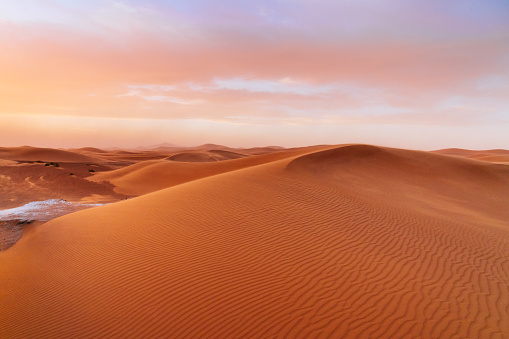 Orange dunes and cloudy sky in Sahara desert. Sunset in the desert.