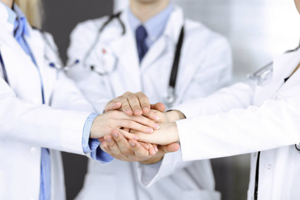 istock Group of modern doctors joining hands as a circle and ready to help patients. Teamwork in medicine during Coronavirus pandemic. Covid 2019 1306329365