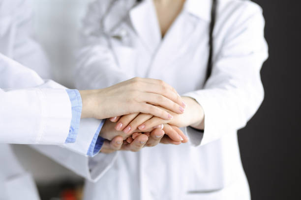 istock Group of modern doctors joining hands as a circle and ready to help patients. Teamwork in medicine during Coronavirus pandemic. Covid 2019 1306329366