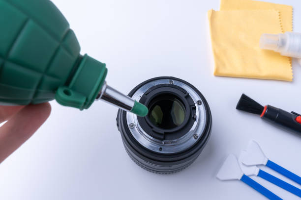istock Photographer blows bullets from the camera lens. Camera cleaning accessories on white background 1306330373