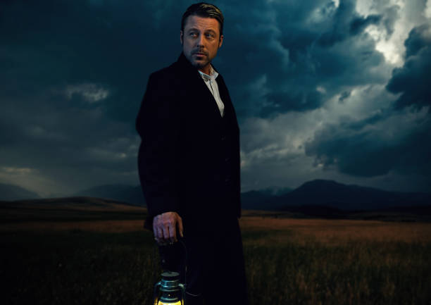 istock Man in victorian clothing with lantern standing on prairie area. 1306333603
