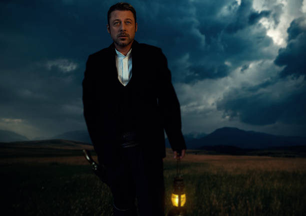 istock Man in victorian clothing with lantern standing on prairie area. 1306333611