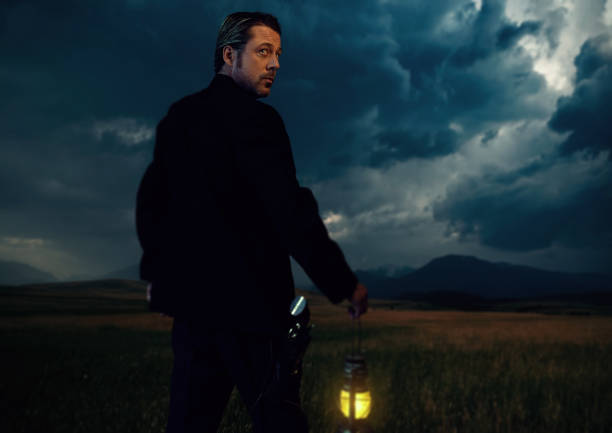 istock Man in victorian clothing with lantern standing on prairie area. Rear view. 1306333622