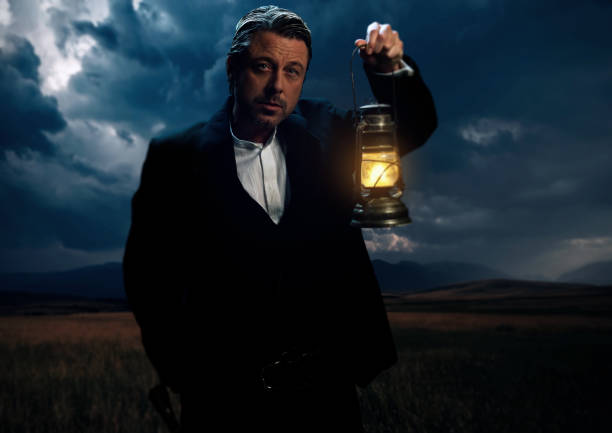 istock Man in victorian clothing with lantern standing on prairie area. 1306333624