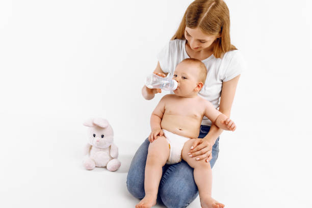 istock Happy smiling mother feeding her baby from a bottle, on white background 1306334897