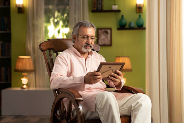 shot of a mature man sitting on rocking chair at home:- stock photo - kurta imagens e fotografias de stock