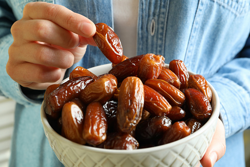 Woman in jeans shirt hold bowl of dates