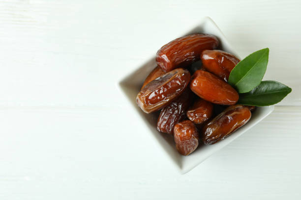 istock Bowl with dried dates on white wooden table 1306335334