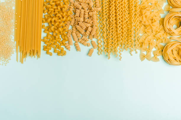 istock Different types of pasta from wheat varieties laid out in a line on a light wine background, copy space on banner 1306336596