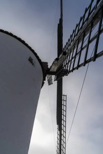 Photo of close up detail view of a whitewashed windmill under a blue and cloudy sky