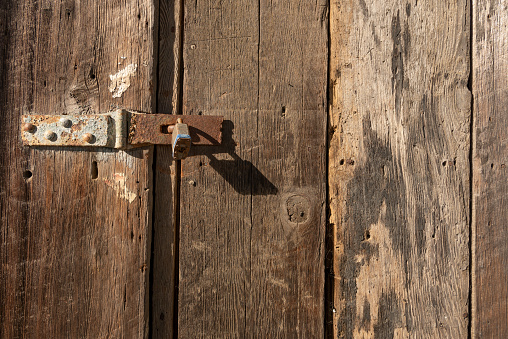 Old rusty lock on old wooden door, illustrating the concept of an abandoned place or a door closed long ago