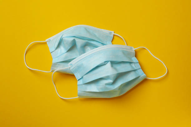istock Two protective medical masks on yellow background 1306338088