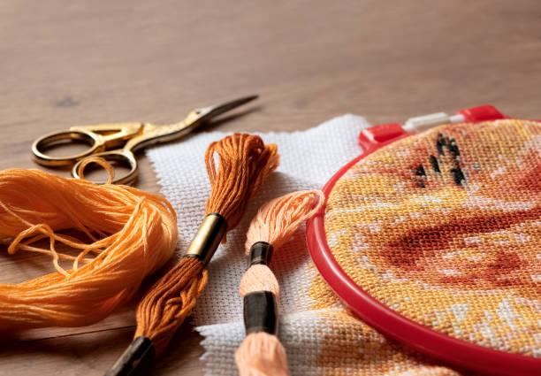 자수 프레임에 자수 크로스 패턴이 있는 캔버스, 컬러풀한 치실실, 가위 옆에 놓여 있습니다. 크로스 스티치, 취미 및 레크리에이션, 그것을 직접 개념 - cross stitch embroidery skeins thread 뉴스 사진 이미지