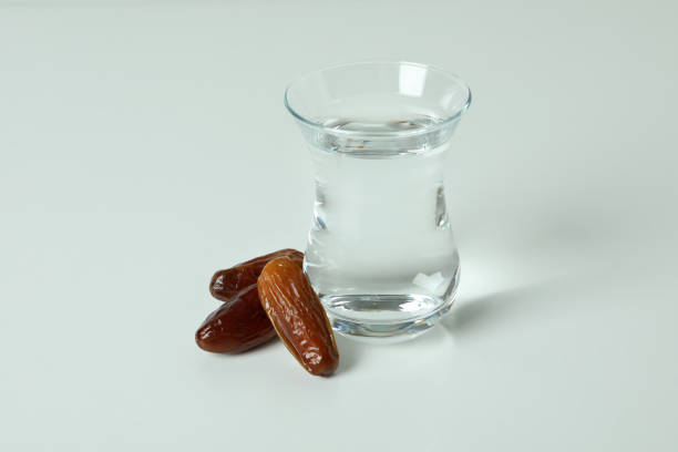 istock Glass of water and dates on white background 1306341440
