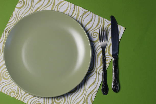 istock Green mate plate on green background with napkin, knife and fork 1306341776