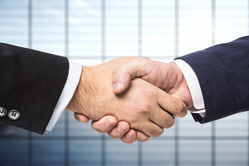 Handshake of two businessmen on the background of empty office, partnership concept, close up