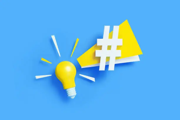 Yellow light bulb with white hashtag symbol sitting on blue background. Horizontal composition with copy space. Creativity, idea, online messaging and social media concept.