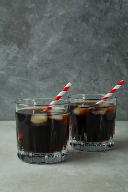 istock Glasses of cola on white textured table against gray background 1306342942