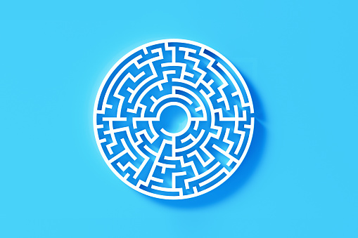 Circular white maze on blue background. Horizontal composition with copy space. Directly above. Solution concept.