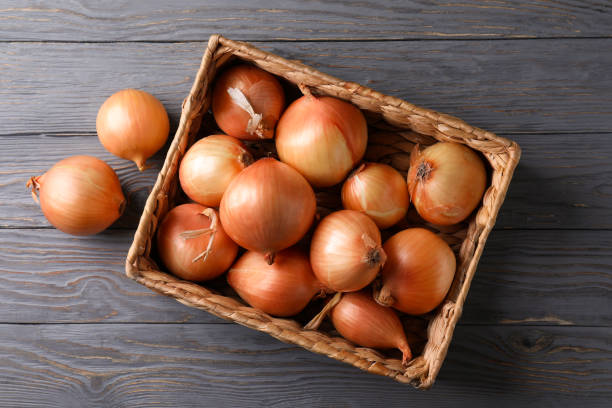 istock Basket with fresh onion on wooden background 1306344699