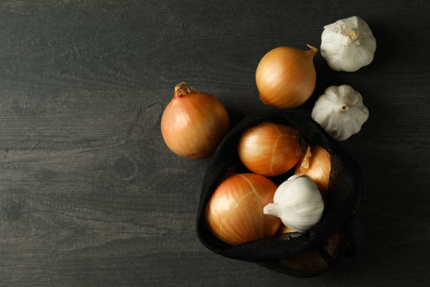 istock Bag with onion and garlic on black wooden table 1306344712