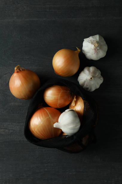 istock Bag with onion and garlic on black wooden table 1306344909