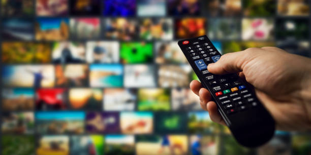 istock tv channels in background and remote control in hand. smart television and content on demand concept 1306345533