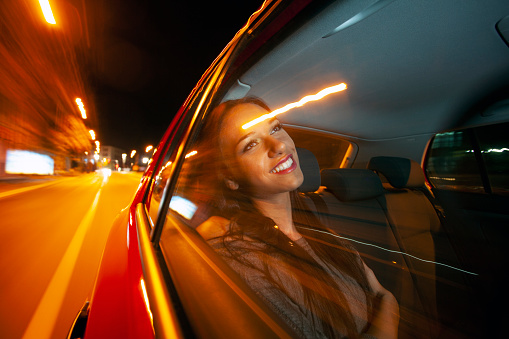 Beautiful woman in a car in motion - urban city scene with motion blur. About 20 years old, Caucasian brunette.