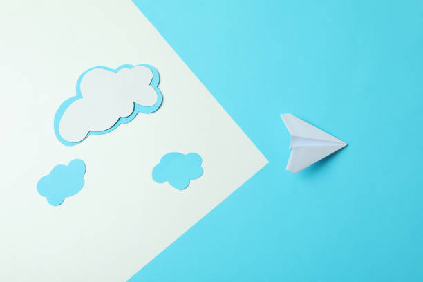 istock Travel concept with paper plane and clouds on two tone background 1306348025