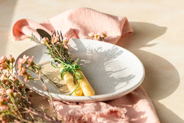 istock Easter table setting background with plate, cutlery set and pink flowers. Empty plate, advertising, menu. Bright sunlight and hard shadows photography trend. 1306348117