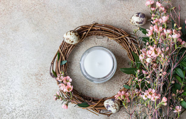 istock Spring composition with braided wreath of twigs with flowers, quail eggs and candle. Easter wreath or nest from rattan. DIY creativity. Top view. 1306349079