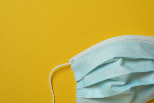 istock Medical mask on yellow background, space for text 1306349563