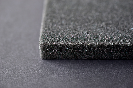 A piece of foam rubber and polystyrene in holes on a black background