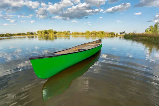 green canoe on a calm lake in a fisheye perspective, late summer in Arapaho Bend Natural Area, Fort Collins, Colorado