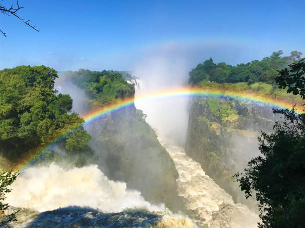 Mosi-oa-Tunya Victoria Falls, Zimbabwe, with a rainbow The iconic Victoria Falls aka Mosi-oa-Tunya waterfall, view from the Zimbabwe side with a rainbow. lake kariba stock pictures, royalty-free photos & images