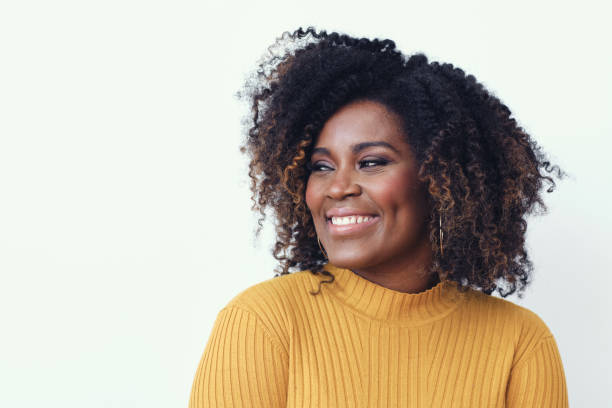 Portrait of a happy young woman smiling Portrait of a happy young woman smiling dressed in a yellow shirt, looking left natural hair stock pictures, royalty-free photos & images